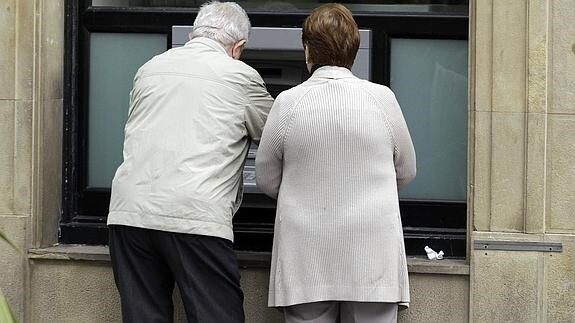 Dos personas mayores sacan dinero de un cajero (archivo). 