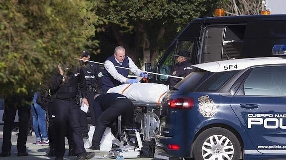 Operarios de la funeraria judicial retiran el cadáver del lugar del crimen.
