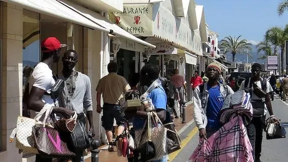 Un grupo de subsaharianos pasea por la ribera de Puerto Banús con una amplia oferta de bolsos falsificados.