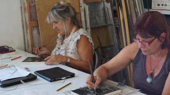Dos mujeres trabajan el grabado. 