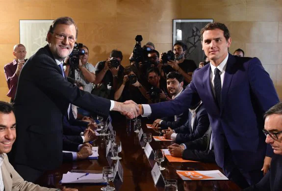 Rivera sella con un apretón de manos con Sánchez y Rajoy los acuerdos de Ciudadanos con PSOE y PP. :: afp