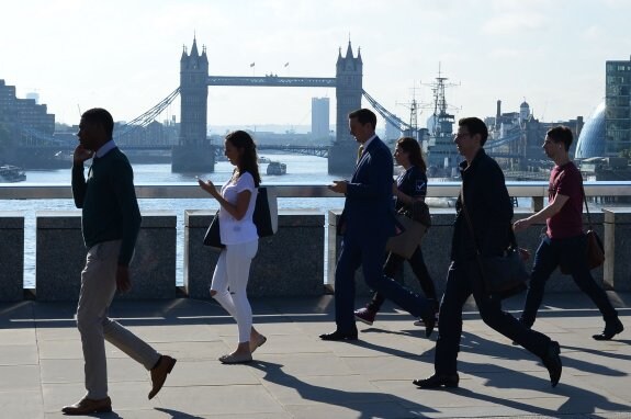 Un grupo de trabajadores de la City atraviesan el Puente de Londres utilizando sus móviles. :: afp