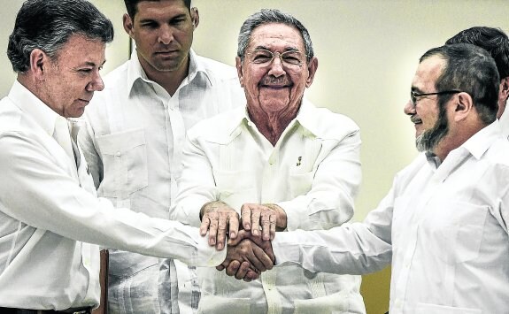 El presidente Juan Manuel Santos estrecha la mano de Timoleón Jiménez, alias 'Timochenko', en presencia de Raúl Castro el día que anunciaron el acuerdo. :: LUIS ACOSTA / AFP
