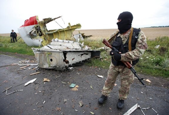 Un rebelde prorruso custodia los restos del avión alcanzado por el misil. :: Maxim Zmeyev / REUTERS