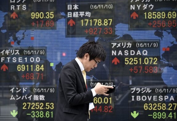 Un hombre pasa por delante de uno de los tableros con los indicadores de la Bolsa de Tokio. :: efe