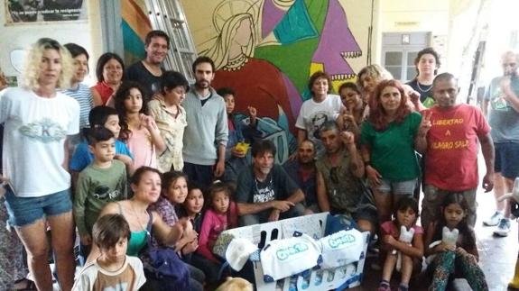 El cura malagueño, en el centro de la imagen, junto a vecinos de Isla Maciel ante un mural reivindicativo.