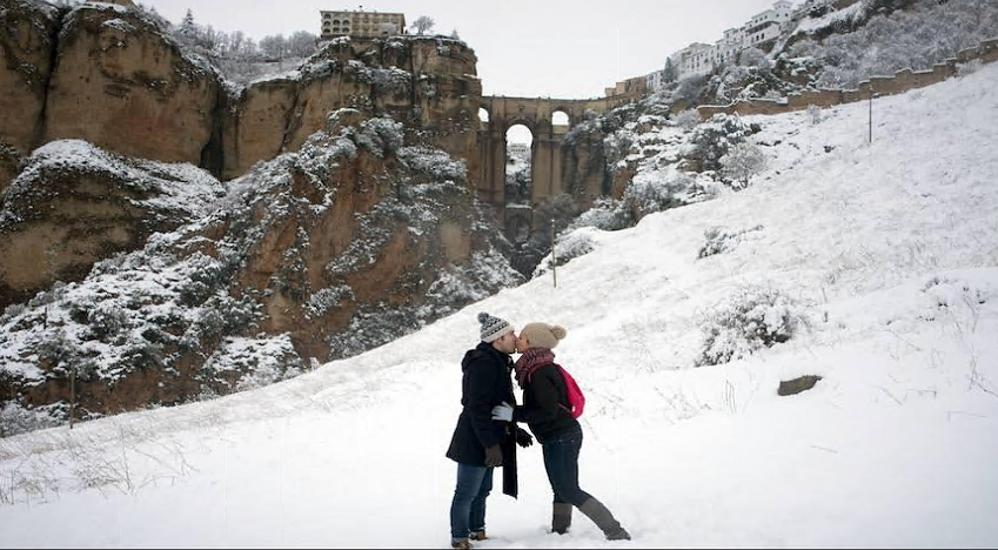 Una pareja se besa frente al Puente Nuevo en Ronda.