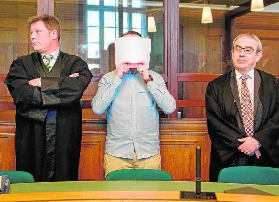 Hamdi H., flanqueado por sus abogados, se cubre el rostro antes de oír la sentencia. :: Gregor Fischer / afp