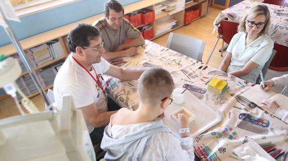 Antonio, voluntario de AVOI, junto a uno de los niños hospitalizados y sus padres