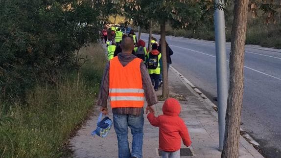 Padres caminan con los niños para llegar al colegio.