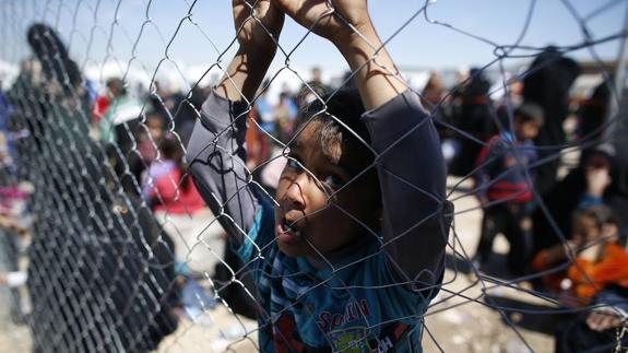 Un niño iraquí se agarra a la valla de un campo de refugiados. 