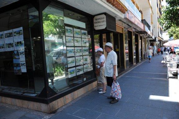 Una pareja de turistas extranjeros, ante el escaparate de una inmobiliaria en Ricardo Soriano.