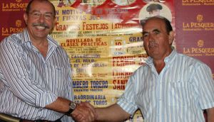 SALUDO. Jesús Soler y Curro Escarcena se dan la mano ante el cartel de los festejos taurinos para la próxima Feria linense. / ÁNGEL