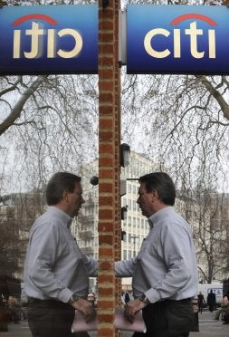 Un hombre, reflejado en la ventana, entra en un banco. / REUTERS
