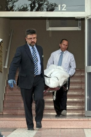 Dos operarios retiran el cuerpo de la fallecida. ::
MORELL / EFE