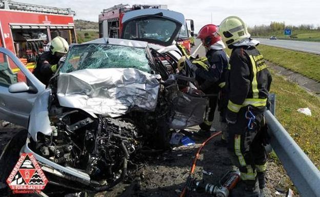 Bomberos intervienen en uno de los vehículos siniestrados en la A-1, en Iruña de Oca. 