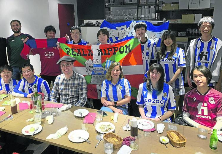 Imagen principal - Miembros de la peña Reala Nippon en Yokohama. Dos seguidoras asiáticas en el Reale Arena y simpatizantes japoneses de la Real con aficionados locales en Anoeta.