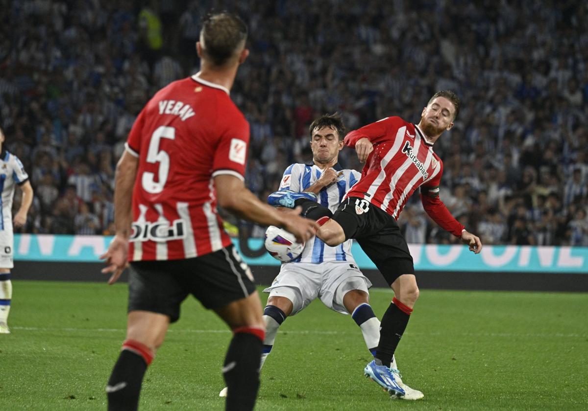 Martin Zubimendi aprieta a Iker Muniain en una balón en el centro del campo.