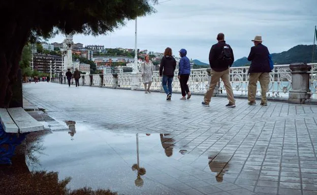 La lluvia no ha impedido que hubiera paseantes en la bahía donostiarra. 