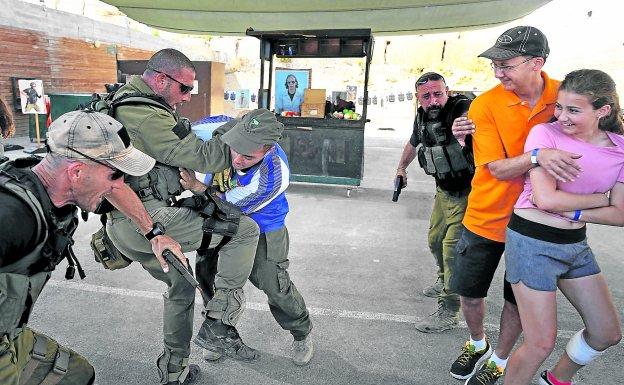 Simulación. Los instructores, antiguos miembros de unidades especiales del Ejército hebreo, repelen un simulacro de agresión con cuchillo junto a dos de sus clientes. 