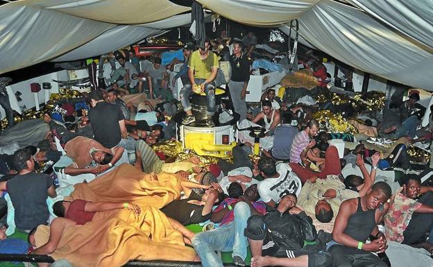 Refugiados rescatados duermen en la cubierta del barco de rescate ‘Open Arms’, en el Mediterráneo Central.