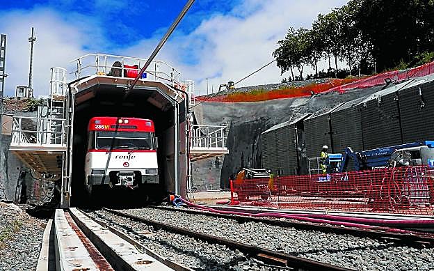 Un tren sale del túnel de Gaintzurizketa, mientras la tuneladora trabaja en la ampliación del gálibo.