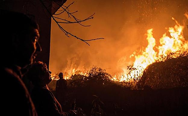 Varias personas observan uno de los incendios en Galicia. 