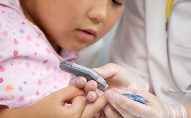 Un médico mide el nivel de glucosa a una niña. 