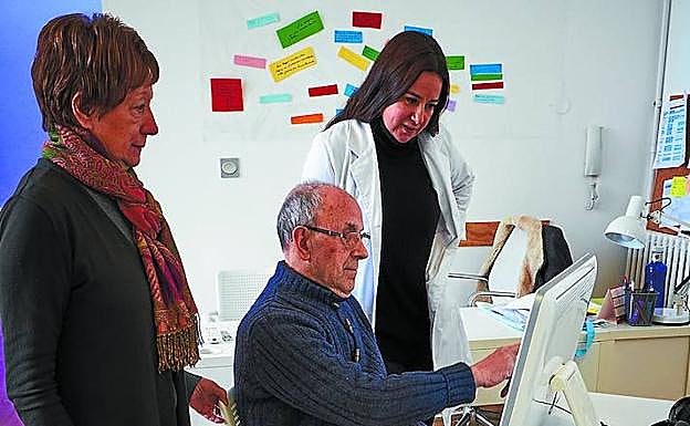 Rogelio trabaja en el ordenador acompañado por su mujer y una de las psicólogas del centro. 