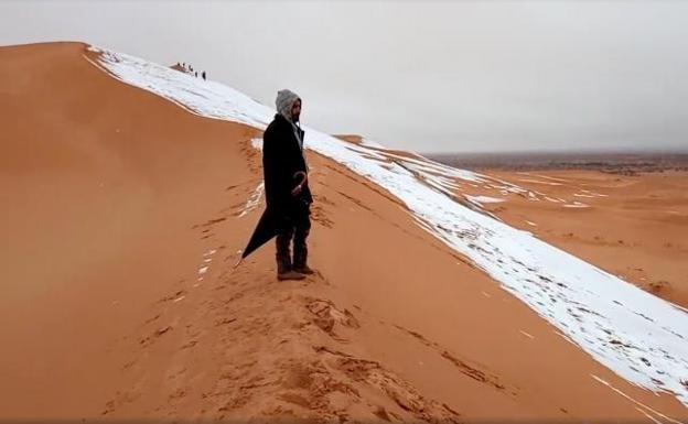 Un hombre observa la nieve en el Sáhara.