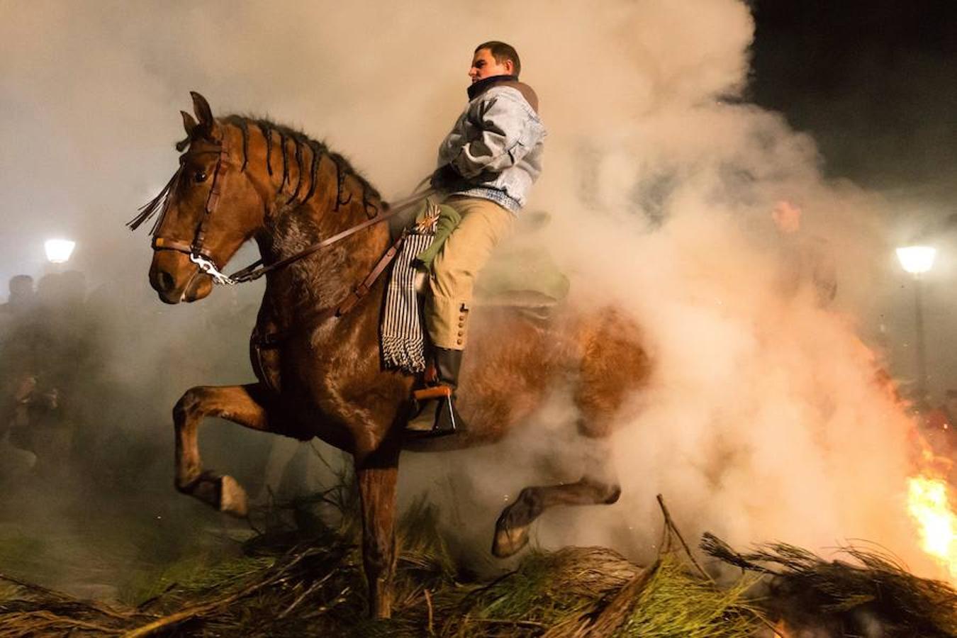 Varios jinetes salta sobre una hoguera en el pueblo de San Bartolomé de Pinares en la provincia de Ávila durante la inauguración de la tradicional fiesta religiosa 'Luminarias' en honor a San Antonio Abad.