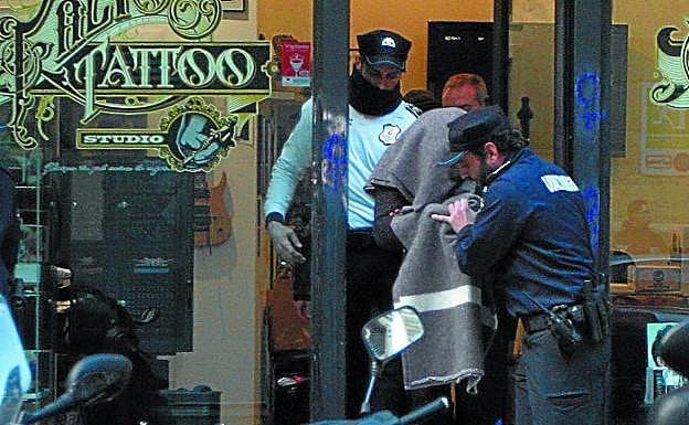 El tatuador es conducido por los agentes tras haber participado en el registro de su local.