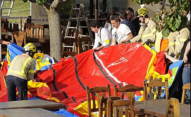 Operarios y bomberos retiran el castillo hinchable donde se produjo el accidente.