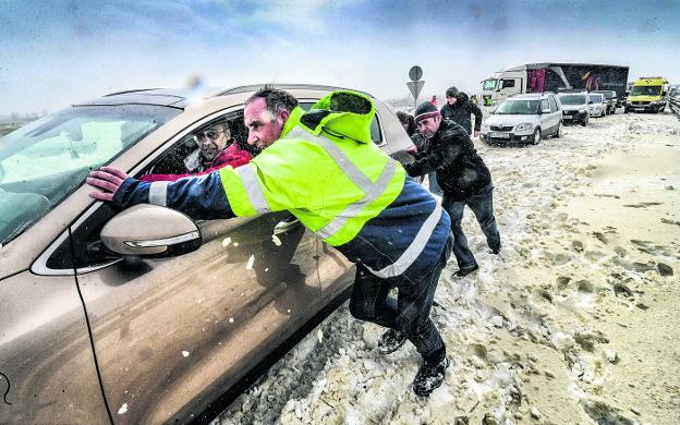 Trabajadores de la Diputación alavesa y voluntarios empujan un coche en la A-1. 