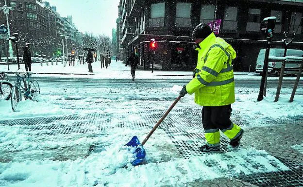Un operario de limpieza se afana en retirar la nieve de las aceras de la calle Urbieta.