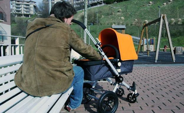 Un padre cuida de su hijo junto a un parque.