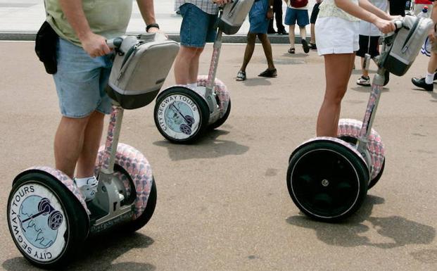 Varias personas montan un patinete eléctrico. 