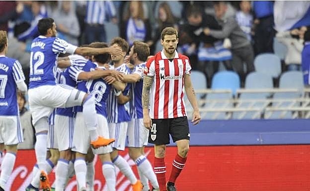 Iñigo Martínez camina cabizbajo mientras los jugadores de la Real celebran un gol en el reciente derbi de Anoeta. 