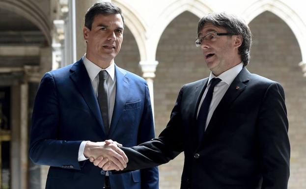 Pedro Sánchez (i) estrecha la mano de Puigdemont. 
