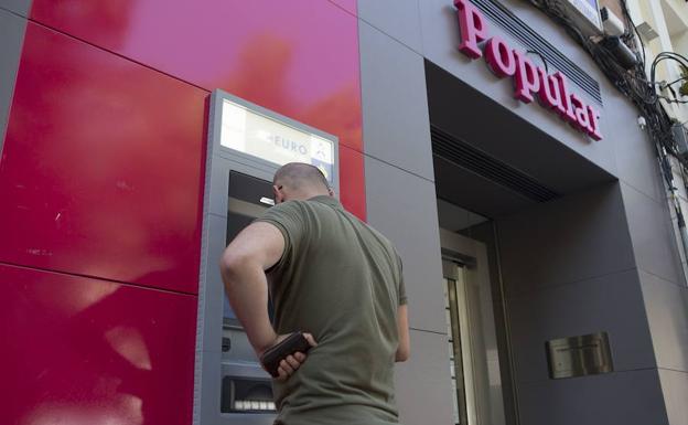 Un cliente saca dinero del cajero de una oficina del Banco Popular en Madrid. 