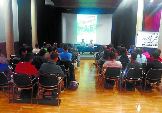 Acto en Trintxerpe. La sala llena con Ekaitz Saies y Xabi Ruiz en la mesa principal dirigiendo el coloquio.
