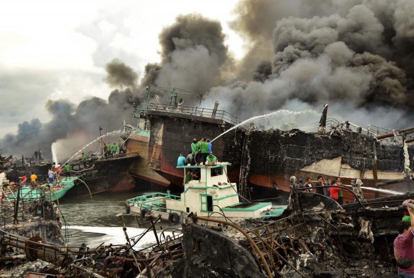 Varios bomberos trabajan en la extinción de un incendio de un barco en el puerto de Benoa, en Bali (Indonesia).
