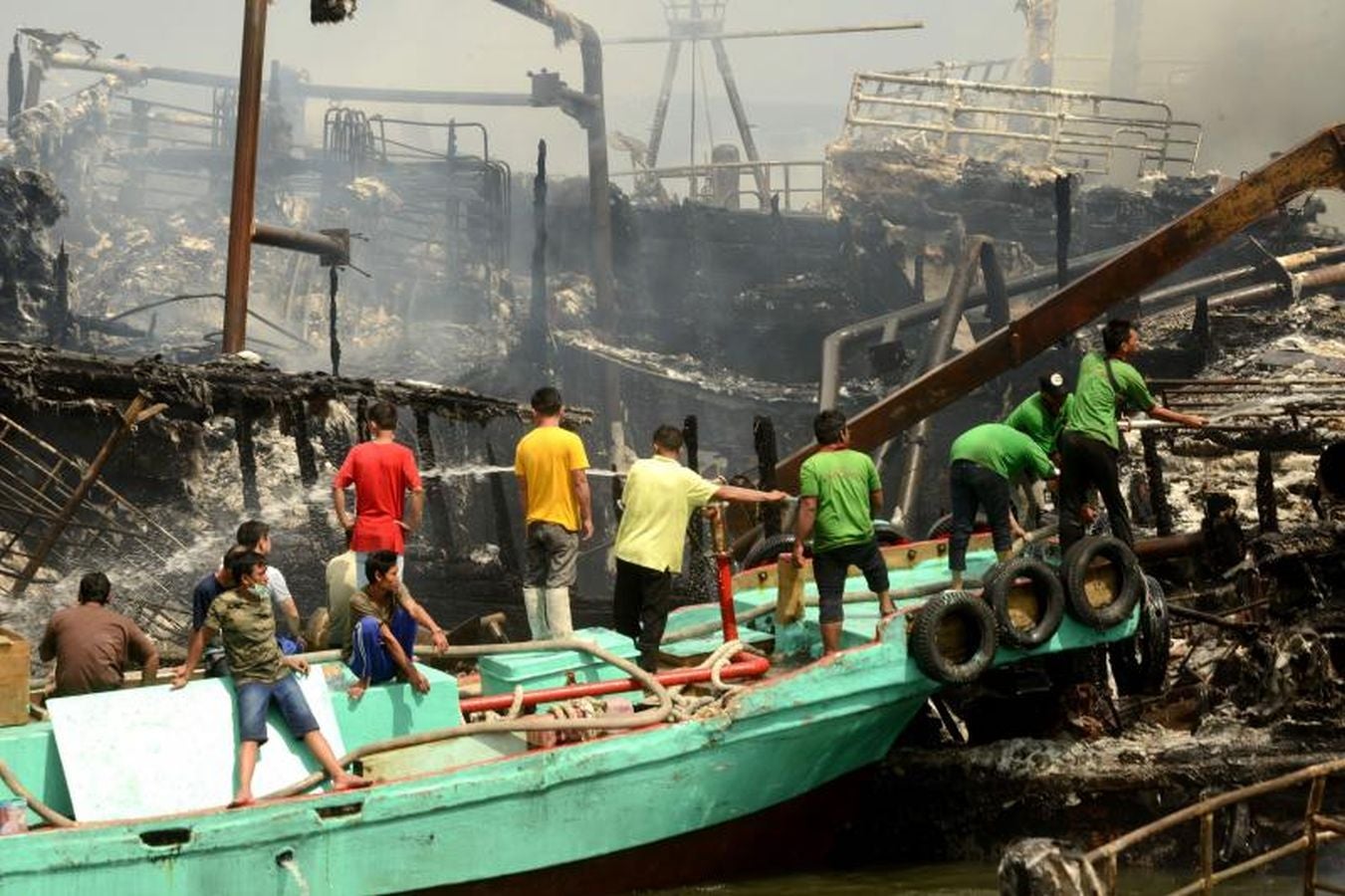 Varios bomberos trabajan en la extinción de un incendio de un barco en el puerto de Benoa, en Bali (Indonesia).