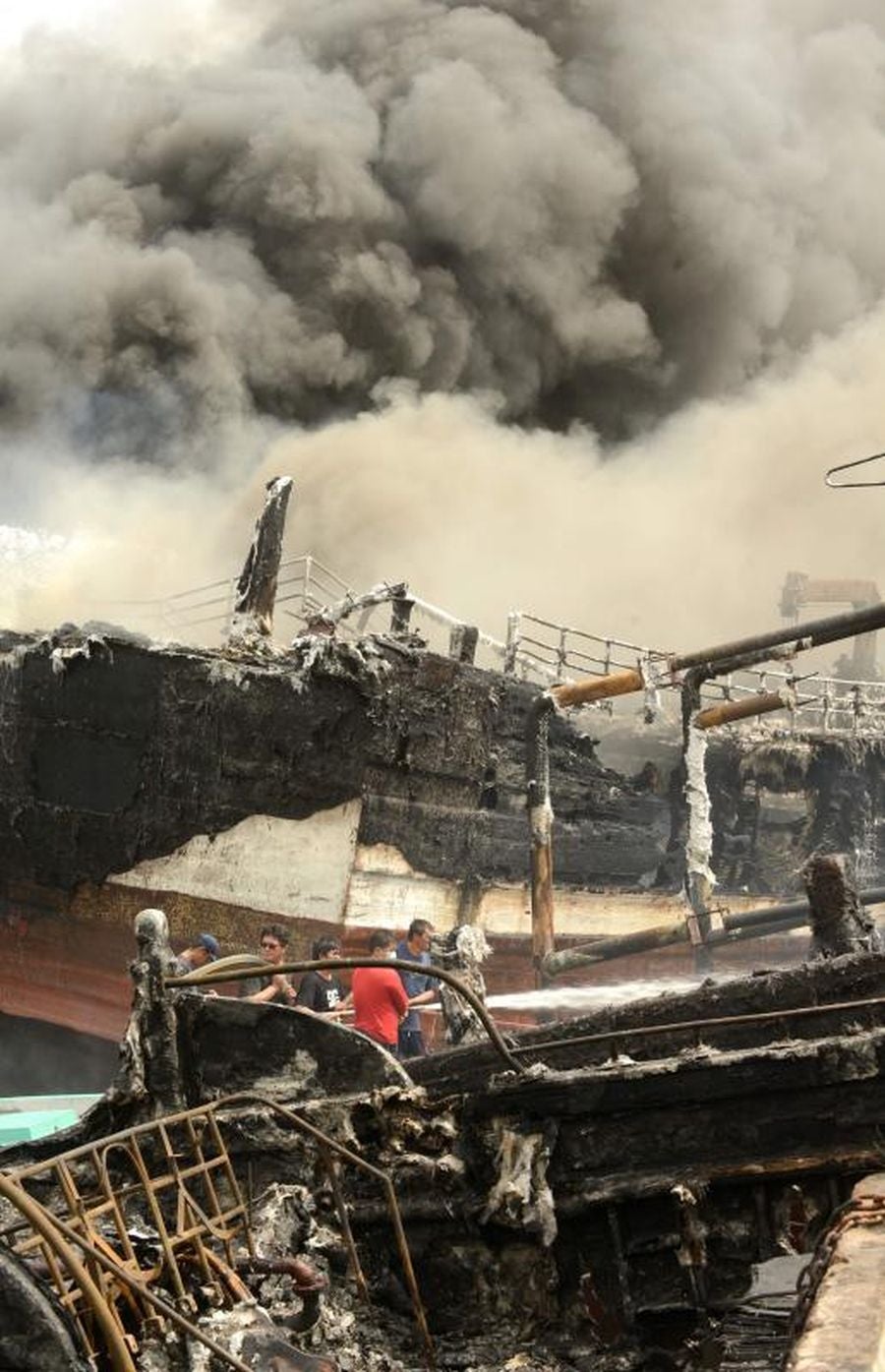 Varios bomberos trabajan en la extinción de un incendio de un barco en el puerto de Benoa, en Bali (Indonesia).