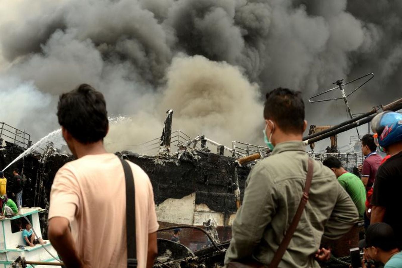 Varios bomberos trabajan en la extinción de un incendio de un barco en el puerto de Benoa, en Bali (Indonesia).