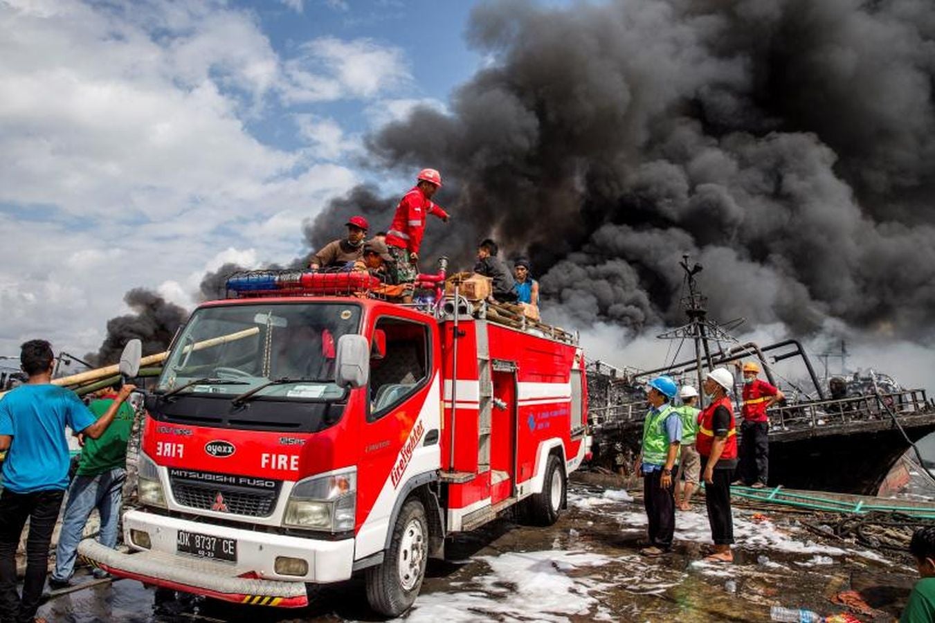 Varios bomberos trabajan en la extinción de un incendio de un barco en el puerto de Benoa, en Bali (Indonesia).