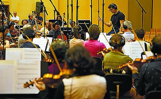 Ángel Alonso y Joseba Beristain saludaron a los músicos. Arriba, Fernando Velázquez dirige a la OSE y un fotograma de la película.