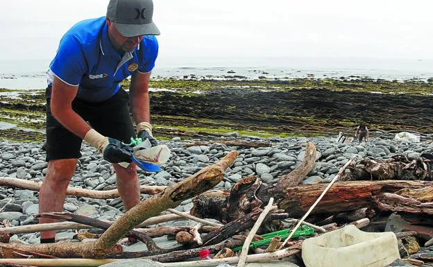 Un voluntario recoge plásticos en el flysh entre Zumaia y Mutriku durante una de las jornadas organizadas para limpiar el Geoparque vasco.