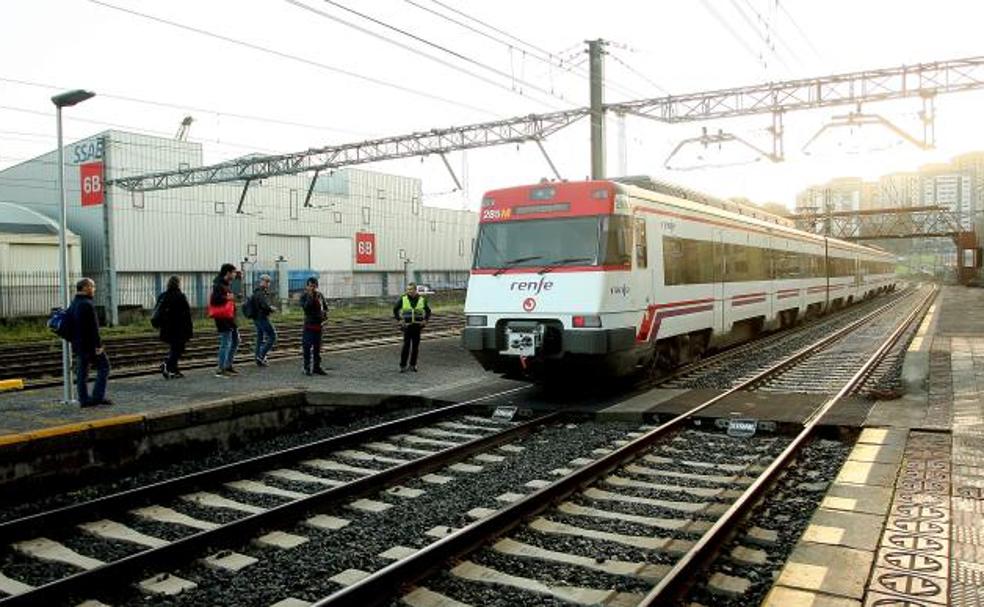 Viajeros esperan que el tren del que acaban de bajar continúe en dirección Irun para atravesar el pasa en la estación de Pasaia