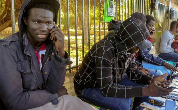 Migratzaile afrikarrak, euren telefonoak kargatzen. 